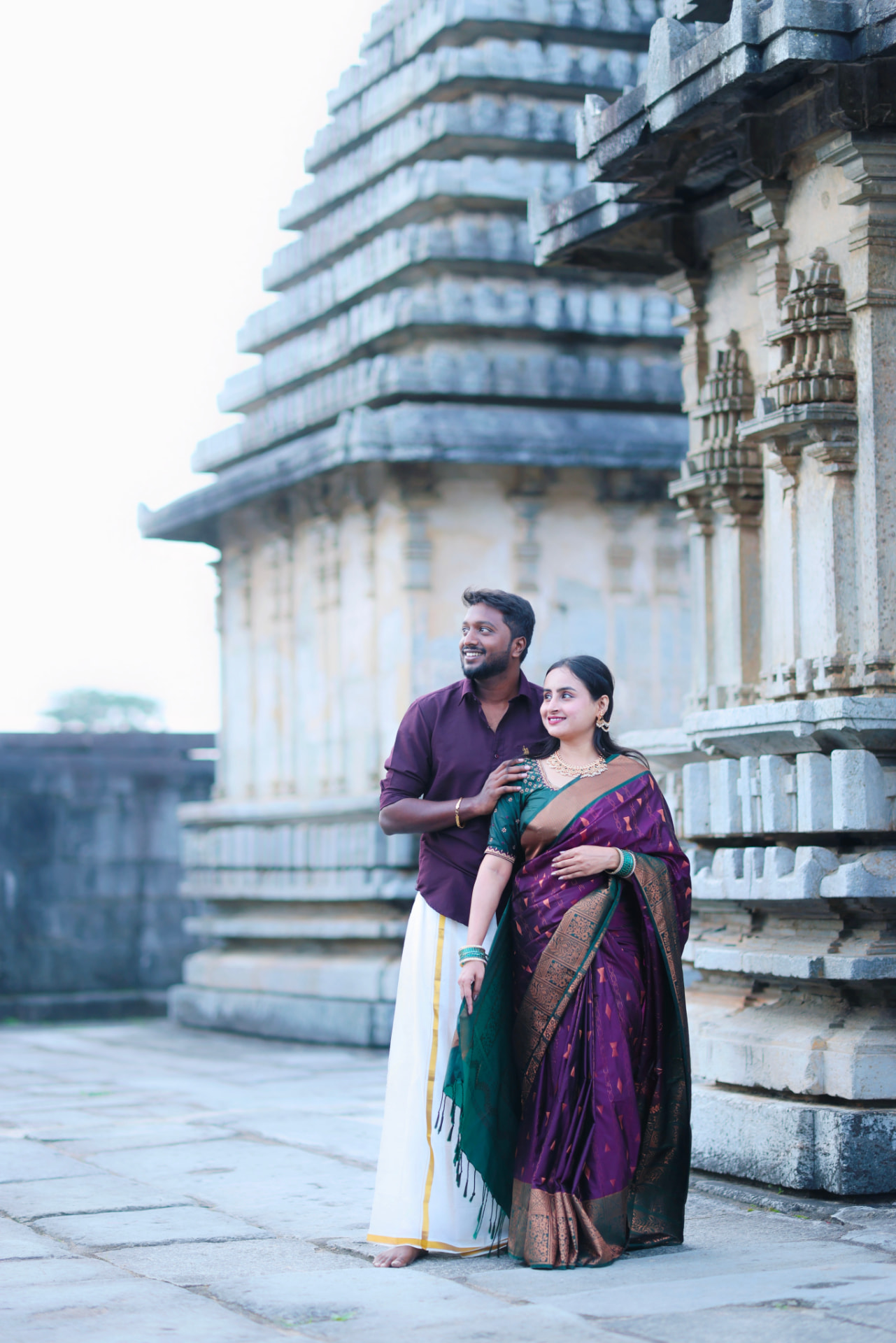 Bhavya and Ajit in traditional South Indian attire at a stone temple